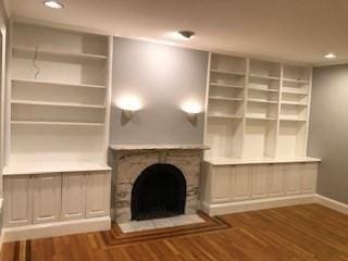 unfurnished living room featuring a fireplace, recessed lighting, wood finished floors, and baseboards