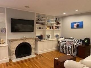 living room with wood finished floors, recessed lighting, a fireplace, and built in shelves