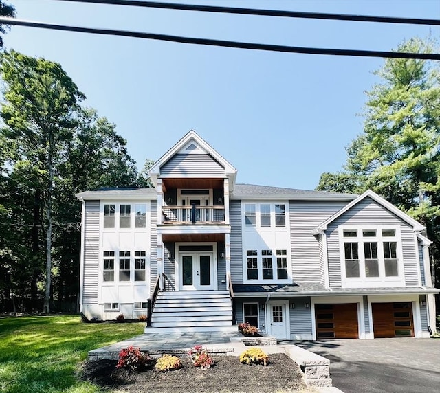 view of front of home featuring a garage, a balcony, a front yard, and french doors