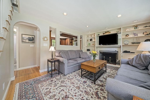 771 Ferry St, Marshfield, MA 02050 - living room with arched walkways, a fireplace with raised hearth, recessed lighting, baseboards, and wood finished floors