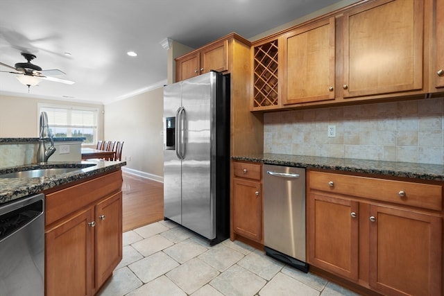 kitchen with decorative backsplash, appliances with stainless steel finishes, ornamental molding, dark stone counters, and sink