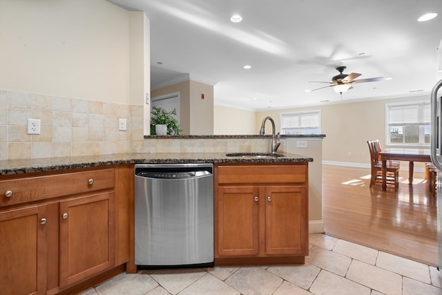 kitchen featuring dark stone countertops, decorative backsplash, dishwasher, and sink