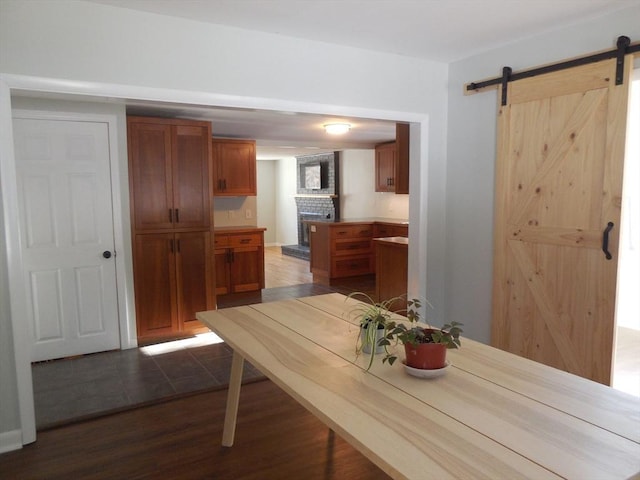 dining space featuring a fireplace, a barn door, and dark hardwood / wood-style floors