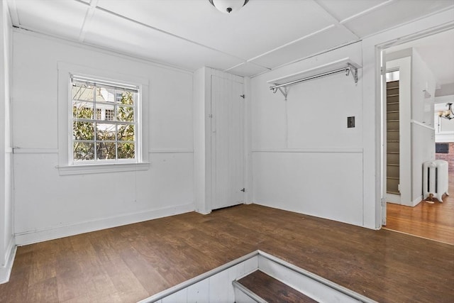 empty room featuring dark wood-type flooring and radiator heating unit