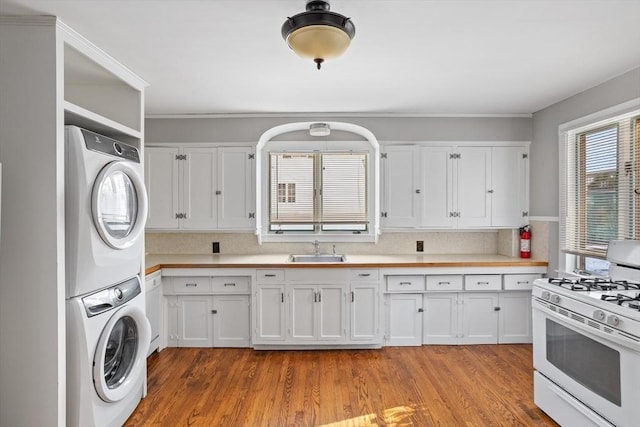 laundry room with stacked washer / dryer, sink, and light wood-type flooring