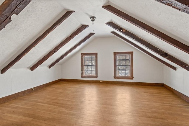 bonus room featuring lofted ceiling, a textured ceiling, and light wood-type flooring