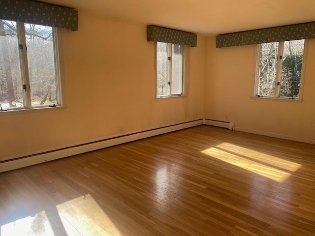 unfurnished room with baseboards, a baseboard heating unit, and wood finished floors