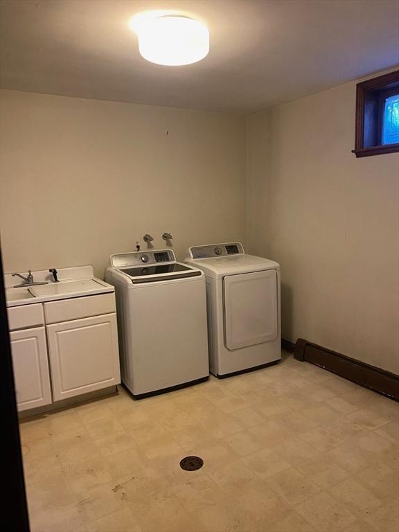 washroom featuring a sink, light floors, washing machine and dryer, and cabinet space