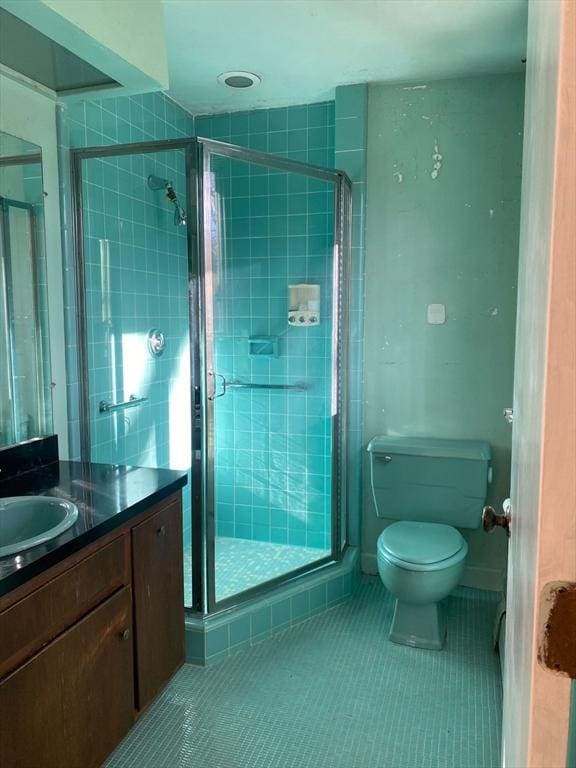 bathroom with toilet, a stall shower, vanity, and tile patterned floors