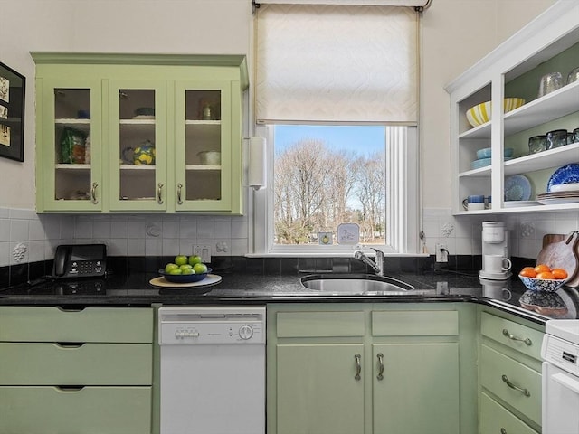 kitchen with a sink, white dishwasher, green cabinetry, decorative backsplash, and stove