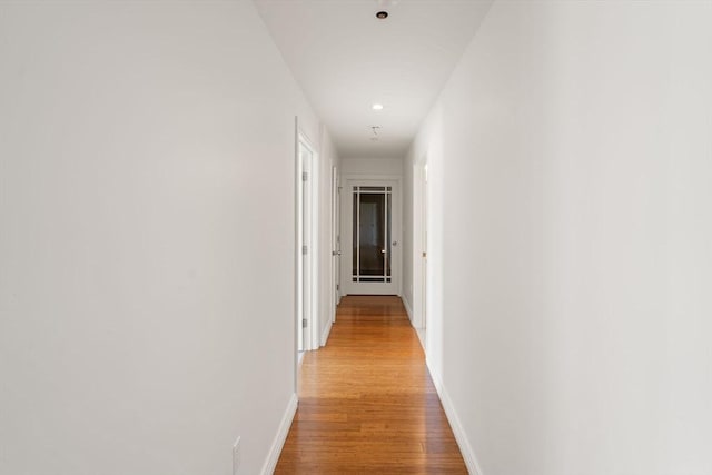 hallway with light wood-style floors, baseboards, and recessed lighting