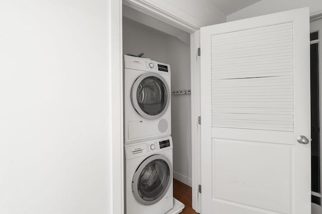 clothes washing area featuring stacked washer and clothes dryer and wood finished floors