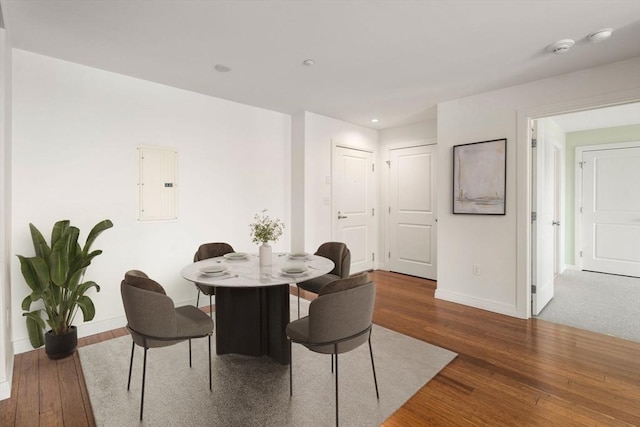 dining area featuring electric panel, baseboards, wood finished floors, and recessed lighting