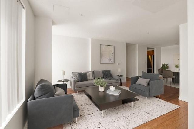 living room with wood finished floors, baseboards, and attic access