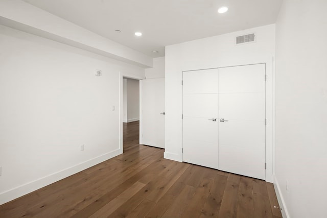 unfurnished bedroom with a closet and dark wood-type flooring