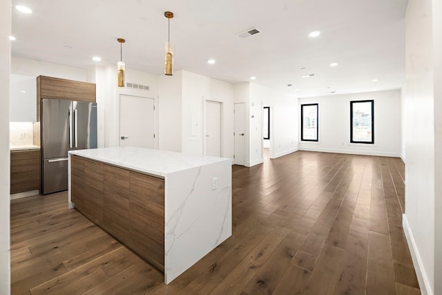 kitchen featuring stainless steel refrigerator, a kitchen island, hanging light fixtures, and dark hardwood / wood-style floors