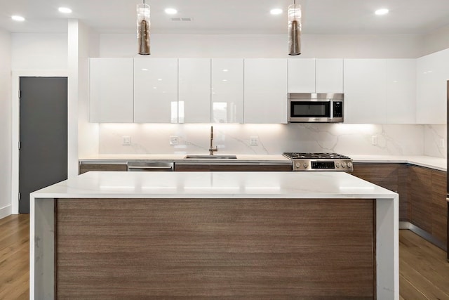 kitchen with appliances with stainless steel finishes, decorative light fixtures, white cabinetry, and dark wood-type flooring