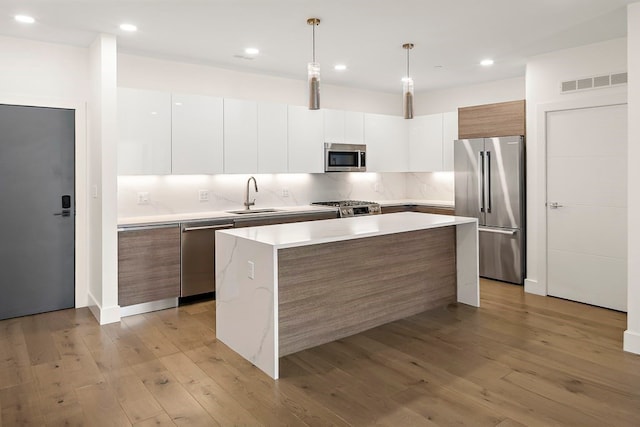 kitchen featuring a center island, light hardwood / wood-style floors, decorative light fixtures, and appliances with stainless steel finishes