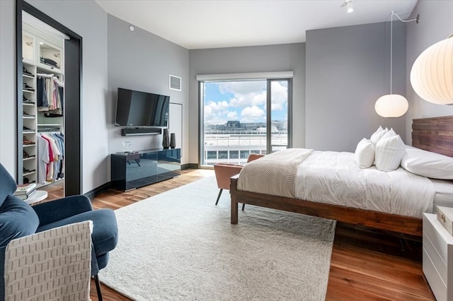 bedroom featuring access to exterior, light wood-type flooring, and a spacious closet