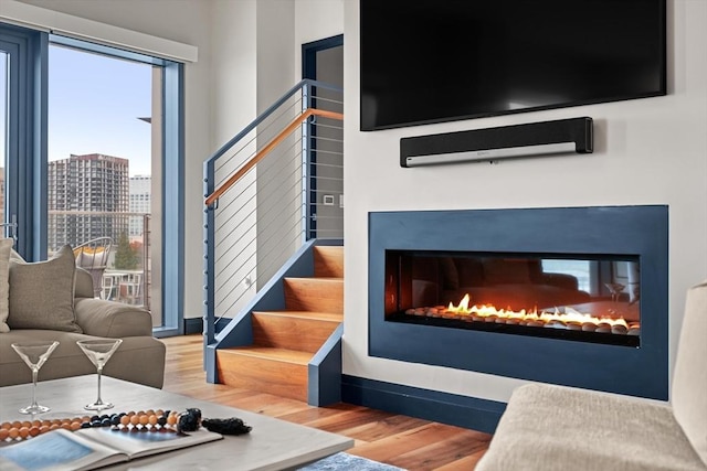 living room with a multi sided fireplace and wood-type flooring