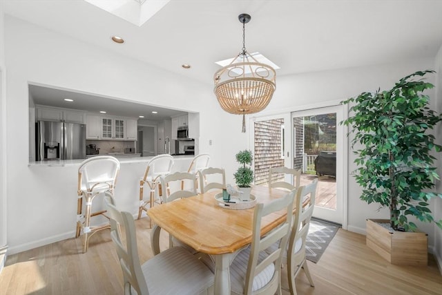 dining room with a skylight, baseboards, a chandelier, recessed lighting, and light wood-style flooring