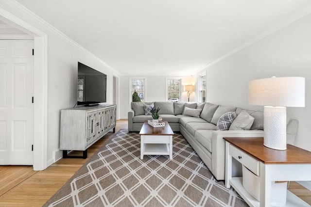 living room featuring crown molding, baseboards, and light wood finished floors