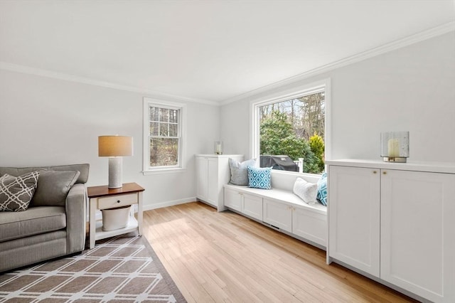 living area with crown molding, baseboards, and light wood finished floors
