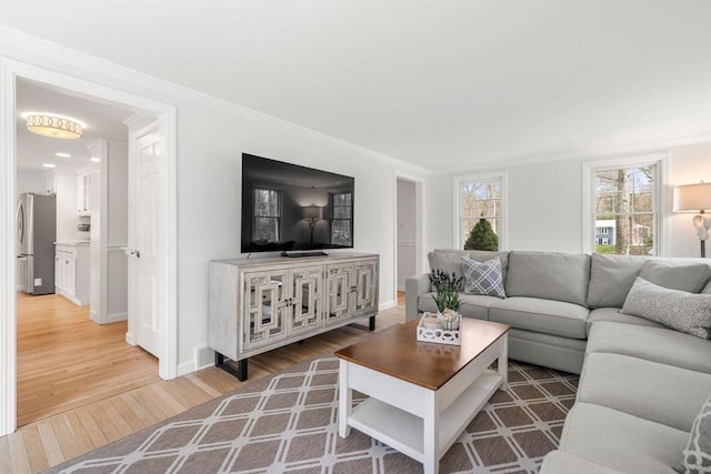 living area featuring crown molding, baseboards, and wood finished floors