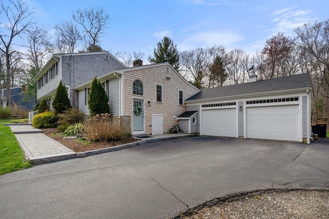 view of side of home featuring an attached garage, driveway, and a chimney