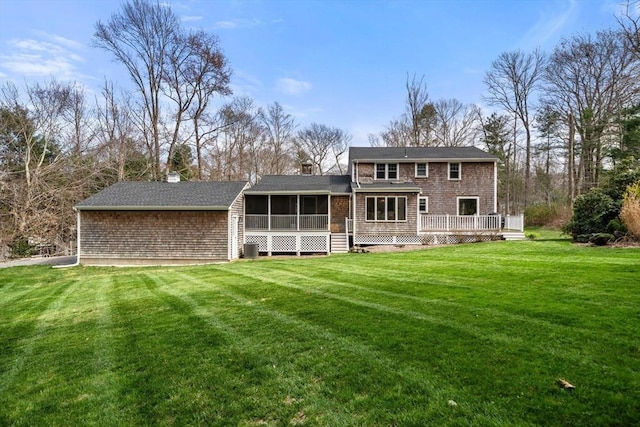 rear view of property with a wooden deck, central AC, a chimney, a sunroom, and a lawn