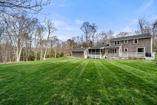 back of property featuring a sunroom, a lawn, and a deck