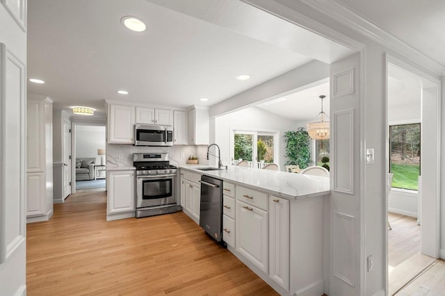 kitchen featuring recessed lighting, white cabinets, a sink, light wood finished floors, and stainless steel appliances