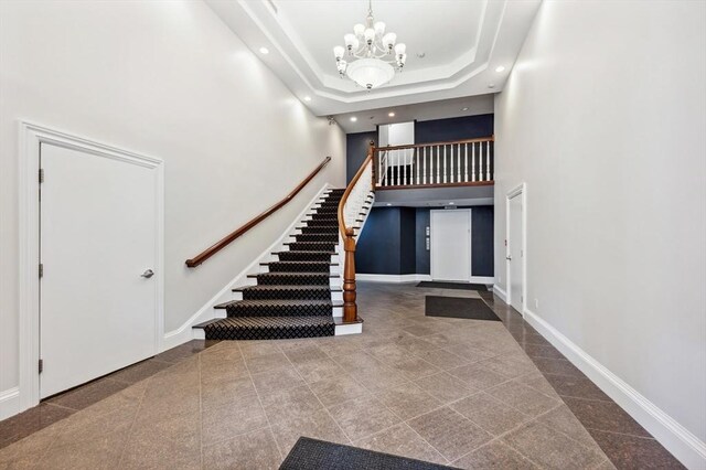 stairs with a high ceiling, a notable chandelier, granite finish floor, recessed lighting, and baseboards