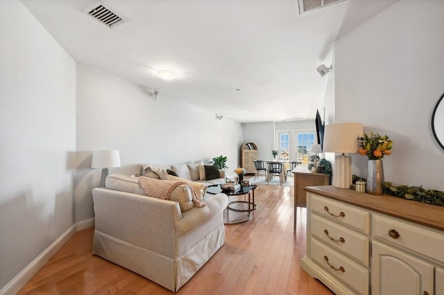 living room with visible vents, light wood-style flooring, and baseboards
