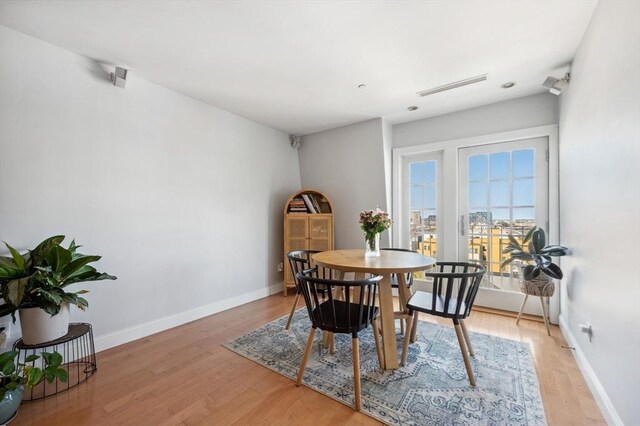 dining area with baseboards, light wood finished floors, and visible vents