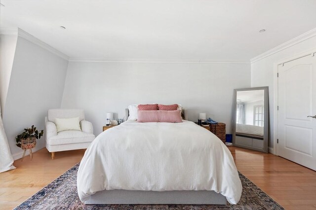 bedroom with ornamental molding and wood finished floors