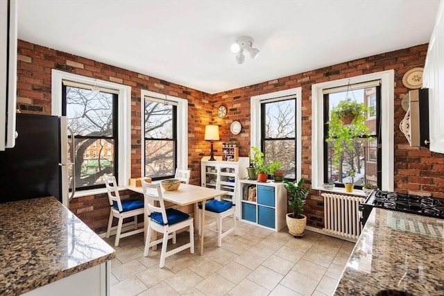 tiled dining room featuring brick wall and radiator heating unit