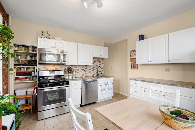 kitchen with sink, white cabinetry, light stone counters, tasteful backsplash, and appliances with stainless steel finishes