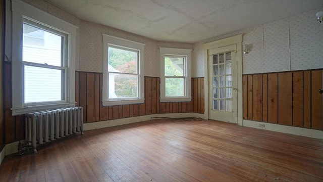 31 Burton St, Springfield, MA 01108 - empty room featuring radiator, wainscoting, wood-type flooring, wallpapered walls, and wood walls