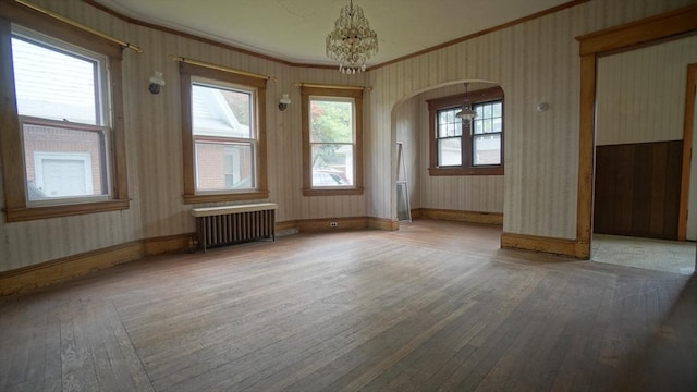 31 Burton St, Springfield, MA 01108 - unfurnished room featuring ornamental molding, radiator heating unit, hardwood / wood-style floors, wallpapered walls, and arched walkways