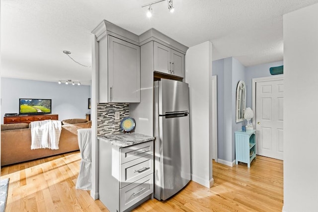 kitchen with freestanding refrigerator, gray cabinetry, rail lighting, and backsplash