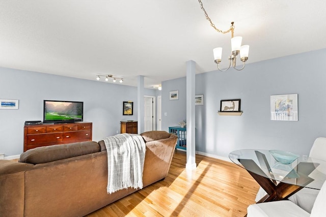 living room featuring an inviting chandelier, wood finished floors, and baseboards