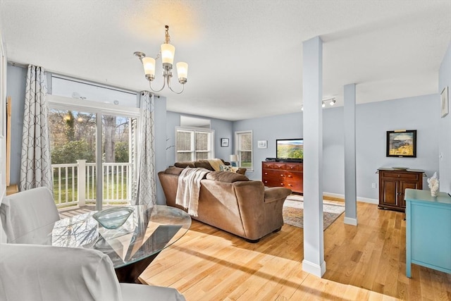 living area with a chandelier, baseboards, and light wood-style floors
