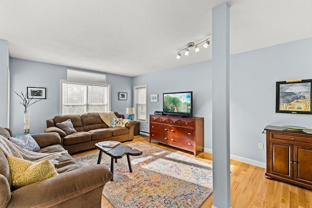 living room with a baseboard heating unit, light wood-style floors, and baseboards
