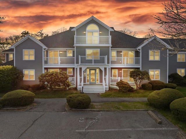back of property at dusk featuring a balcony and covered porch