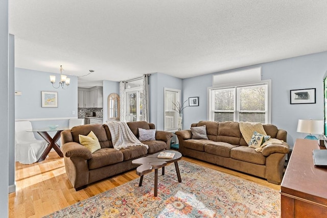 living area featuring a chandelier, a textured ceiling, and light wood-style floors