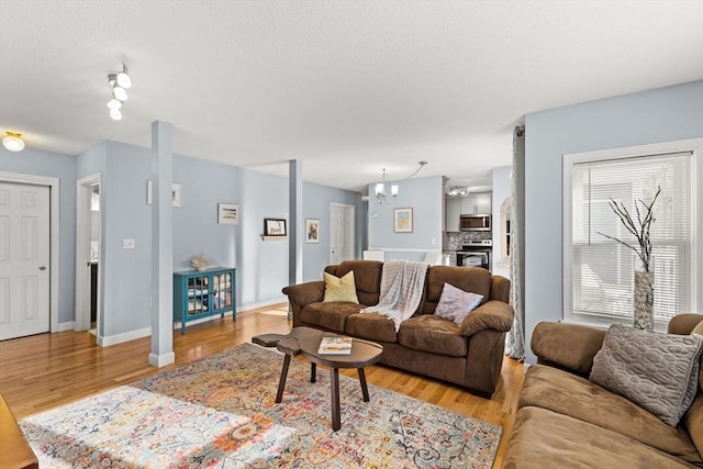 living room with a chandelier, light wood-style flooring, and baseboards