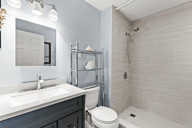 bathroom featuring vanity, toilet, and tiled shower