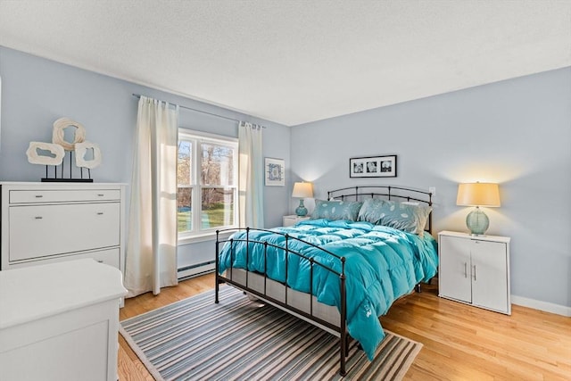bedroom featuring baseboards, baseboard heating, and light wood finished floors