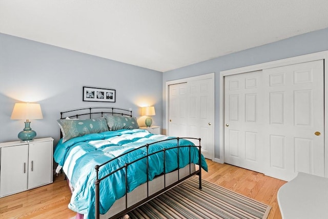 bedroom with two closets and light wood-type flooring